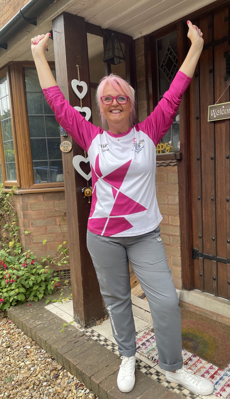 Jules celebrating in a Birmingham 2022 Commonwealth Games baton bearer shirt with arms raised